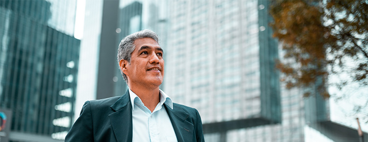 Photo of businessman walking outside surrounded by office buildings.